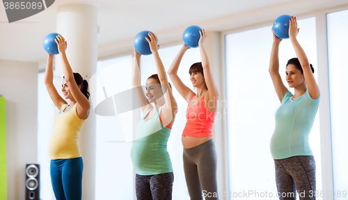 Image of happy pregnant women exercising with ball in gym