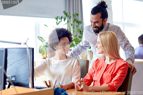 Image of happy creative team with computer in office
