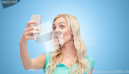 Image of funny young woman taking selfie with smartphone