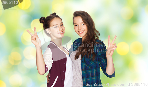 Image of happy teenage girls hugging and showing peace sign