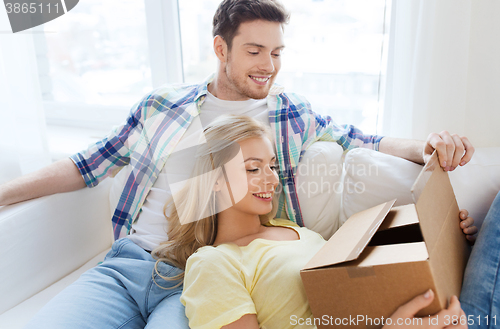 Image of smiling couple with cardboard box at home