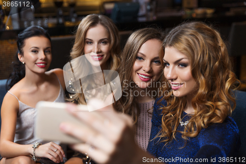 Image of women with smartphone taking selfie at night club