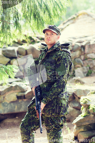 Image of young soldier or hunter with gun in forest