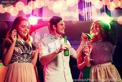 Image of smiling friends with wine glasses and beer in club