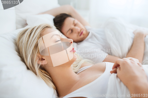 Image of happy couple sleeping in bed at home