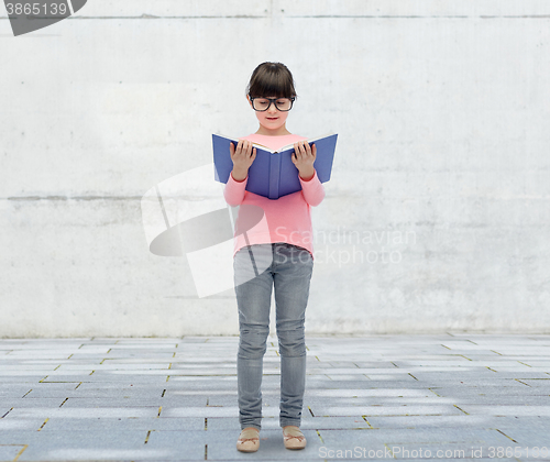 Image of happy little girl in eyeglasses reading book