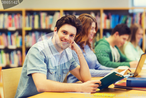 Image of happy student boy reading book in library
