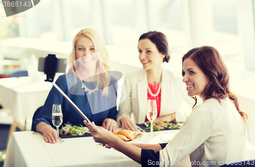 Image of women with smartphone taking selfie at restaurant