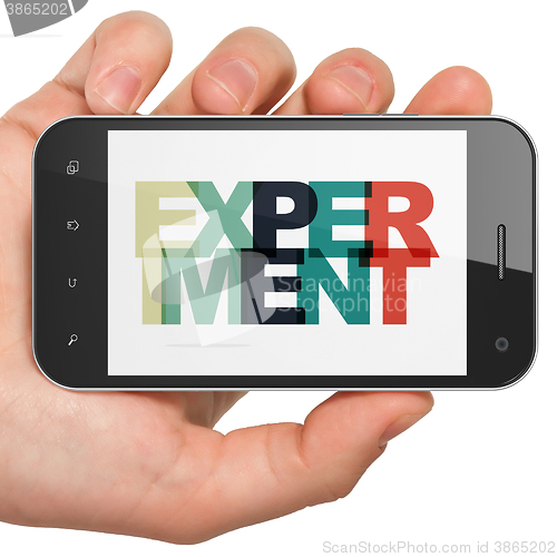 Image of Science concept: Hand Holding Smartphone with Experiment on  display