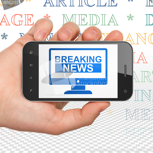 Image of News concept: Hand Holding Smartphone with Breaking News On Screen on display