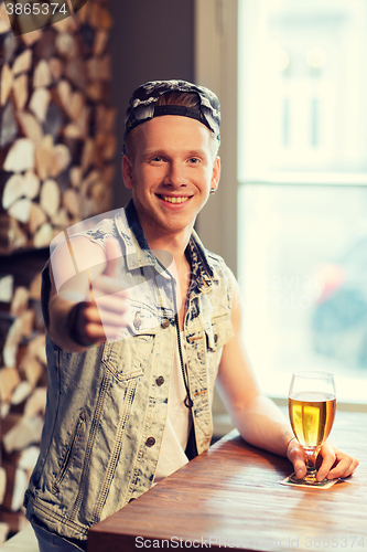 Image of happy man with beer showing thumbs up at bar