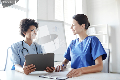 Image of happy doctors with tablet pc meeting at hospital