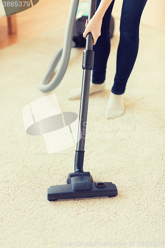 Image of close up of woman legs with vacuum cleaner at home