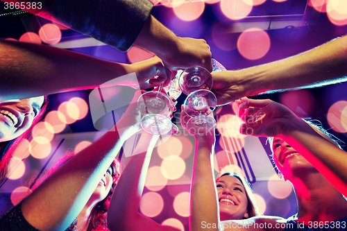 Image of smiling friends with glasses of champagne in club