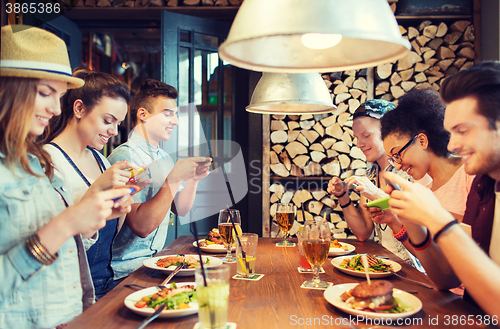 Image of happy friends with smartphones picturing food