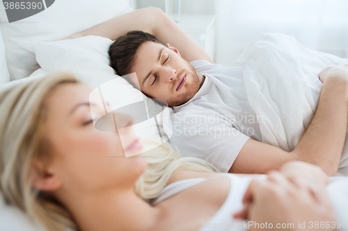 Image of happy couple sleeping in bed at home