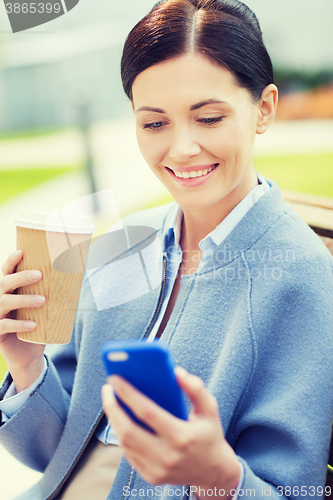 Image of smiling woman with coffee and smartphone