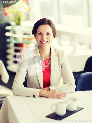 Image of happy woman sitting at table in restaurant