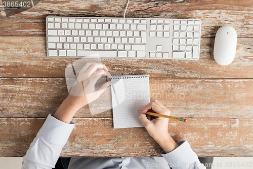 Image of close up of hands with notebook and keyboard