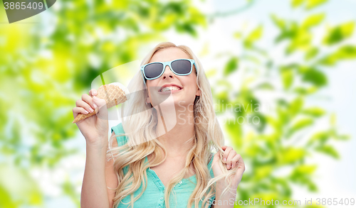 Image of happy young woman in sunglasses eating ice cream