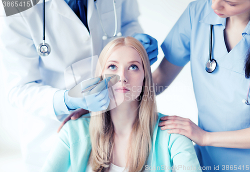 Image of plastic surgeon and nurse with patient