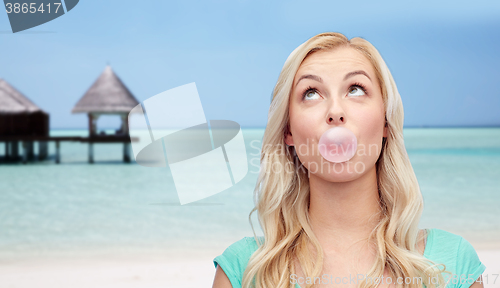 Image of happy woman or teenage girl chewing gum on beach