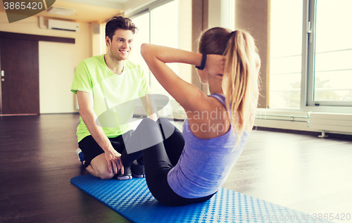 Image of woman with personal trainer doing sit ups in gym