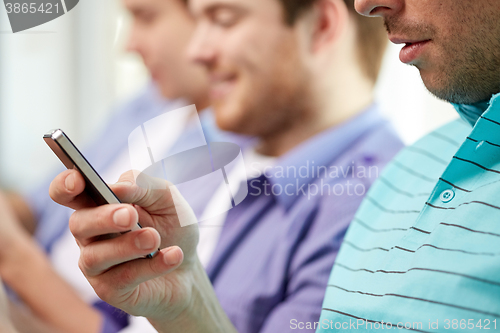 Image of close up of happy friends with smartphones at home