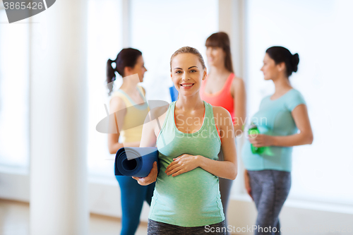 Image of happy pregnant woman with mat in gym