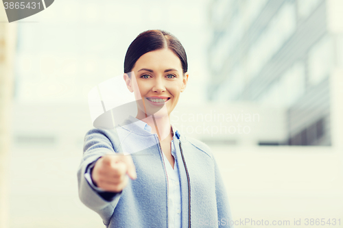 Image of young smiling businesswoman over office building
