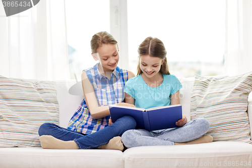 Image of two happy girls reading book at home