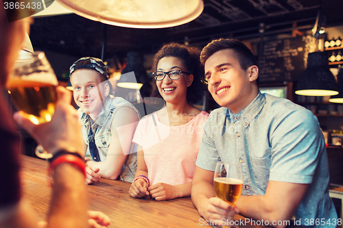 Image of happy friends drinking beer and talking at bar