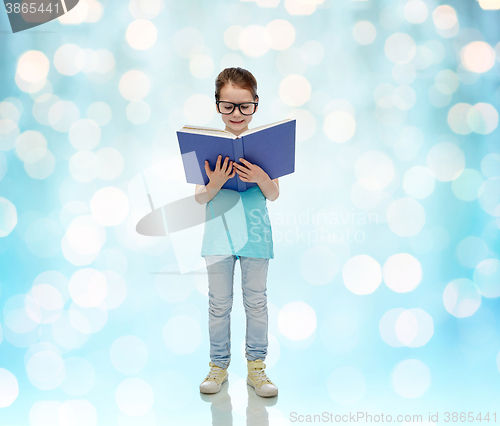 Image of happy little girl in eyeglasses reading book