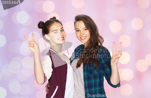 Image of happy teenage girls hugging and showing peace sign
