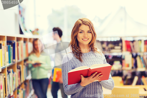 Image of happy student girl or woman with book in library