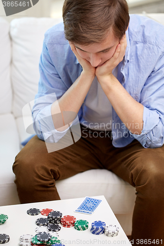 Image of man with playing cards and chips at home