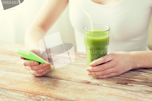 Image of close up of woman with smartphone and green juice