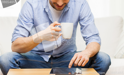 Image of close up of man with tablet pc and tea cup at home