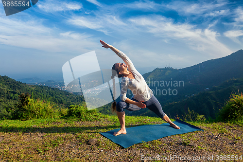 Image of Woman practices yoga asana Utthita Parsvakonasana outdoors