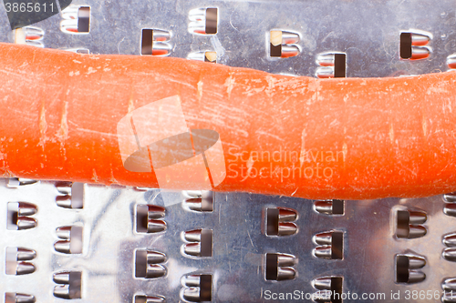 Image of grated carrots. Nearby is grater and carrots