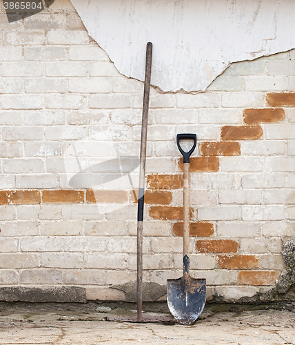 Image of shovel and rake near the wall