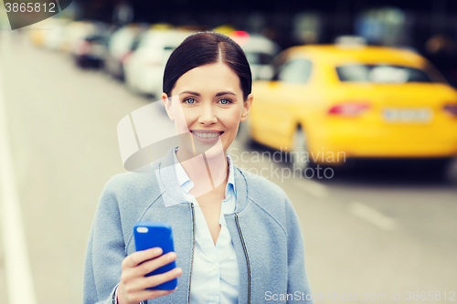 Image of smiling woman with smartphone over taxi in city