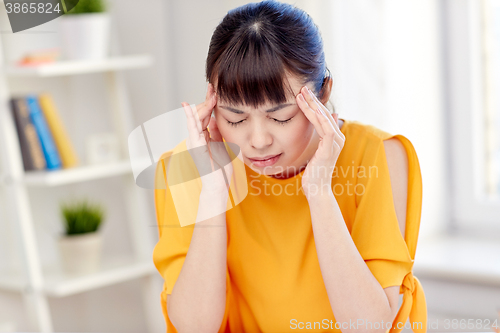 Image of tired asian woman suffering from headache at home