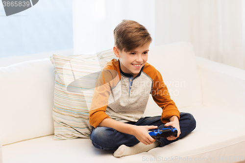 Image of happy boy with joystick playing video game at home