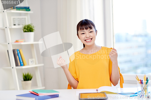 Image of happy asian young woman student learning at home
