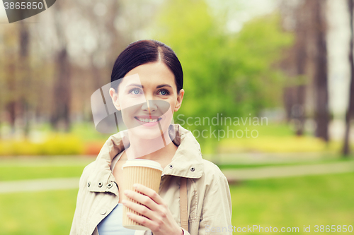 Image of smiling woman drinking coffee in park