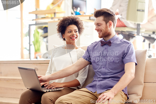 Image of happy creative team with laptop in office