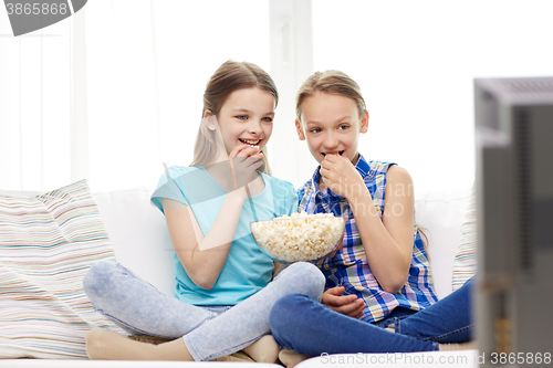 Image of happy girls with popcorn watching tv at home