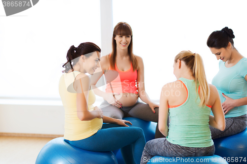 Image of happy pregnant women sitting on balls in gym