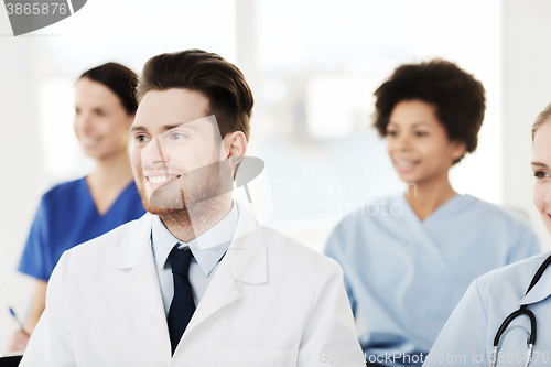 Image of happy doctor over group of medics at hospital